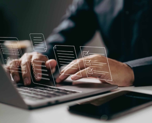 Typing On A Laptop With Digital Documents And Checklists Floating Above