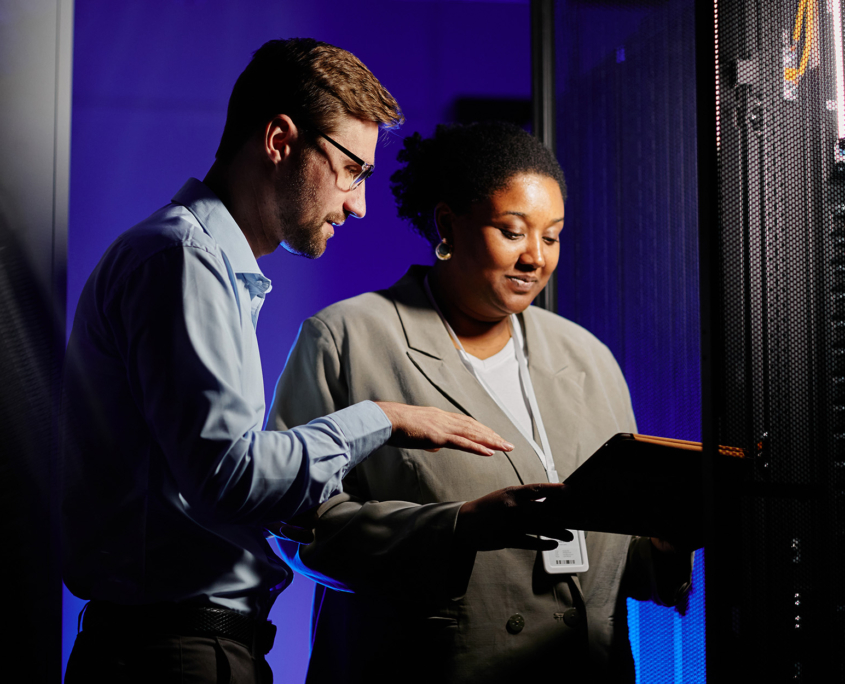 People In Server Room Looking At Laptop