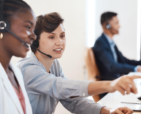 Workers With Headsets Looking At Computer While On Calls