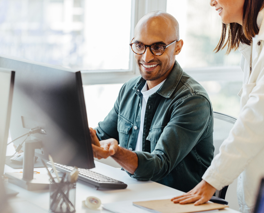 Workers In Office Looking At Computer Monitor