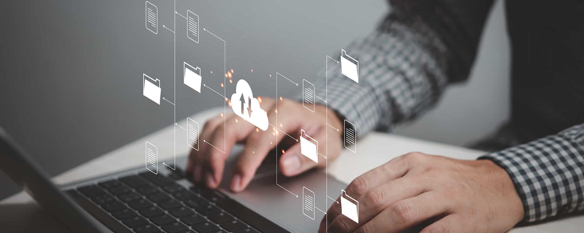 Side view of man typing on laptop with cloud graphics hovering over keyboard